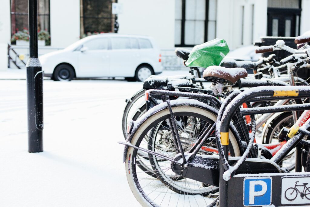 Modern bicycles parked on street covered with snow on winter day in city district